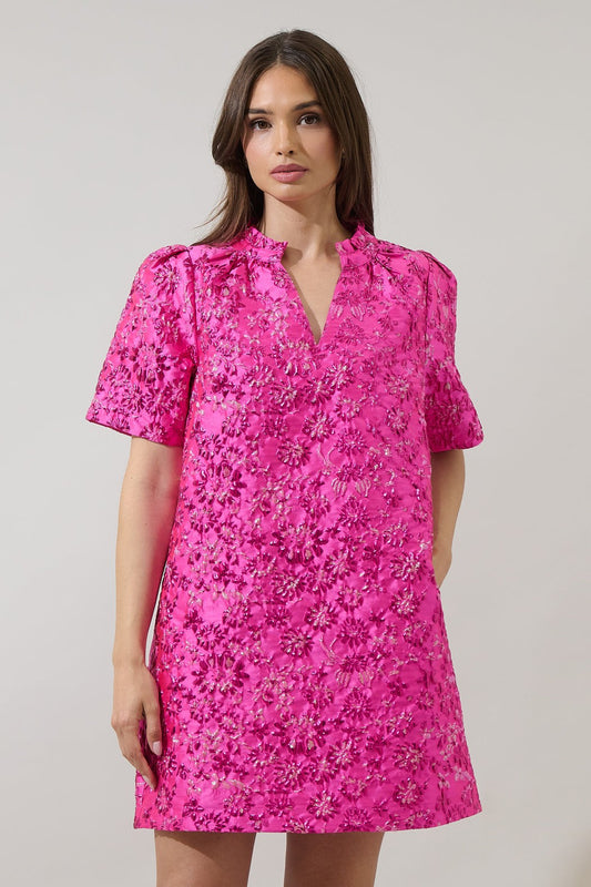 Model wearing The Pink Posh Mini — a fuchsia floral embroidered short-sleeve dress with shimmer details and a ruffle neckline from Milo & Lily Boutique.