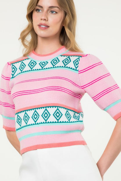 Close-up of pink striped knit top with teal diamond pattern and colorblock trim — feminine boutique knitwear style.