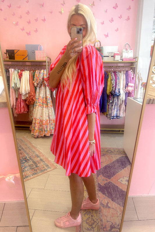 Person wearing a red and pink striped dress in a clothing store.