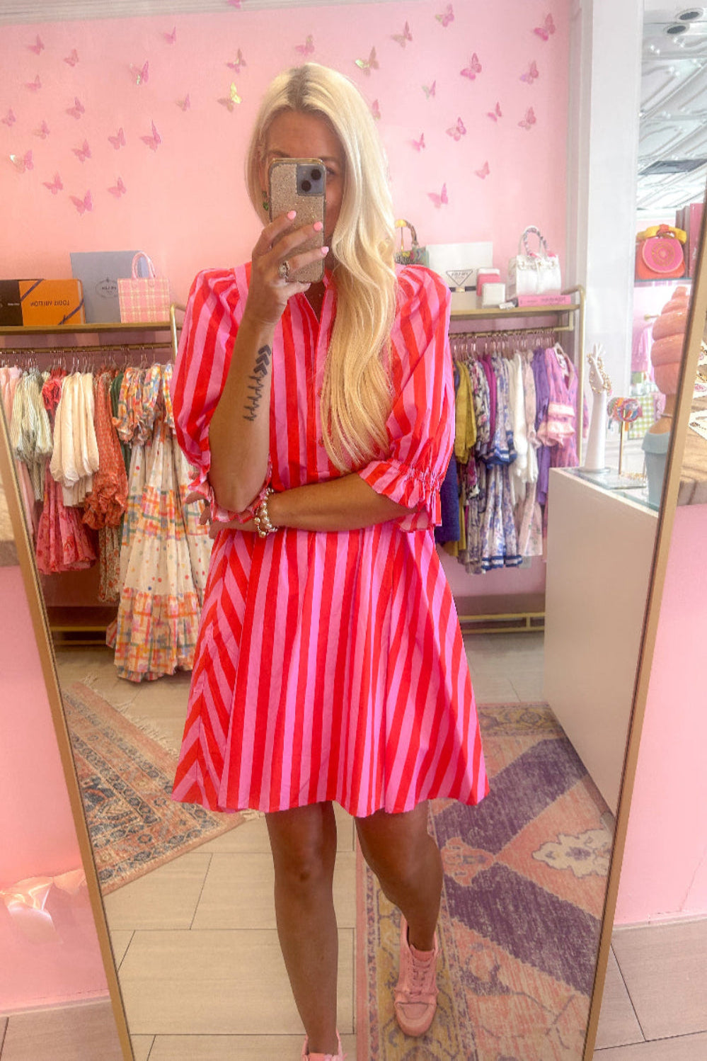 Person wearing a red and pink striped dress in a store with pink walls and butterfly decorations.