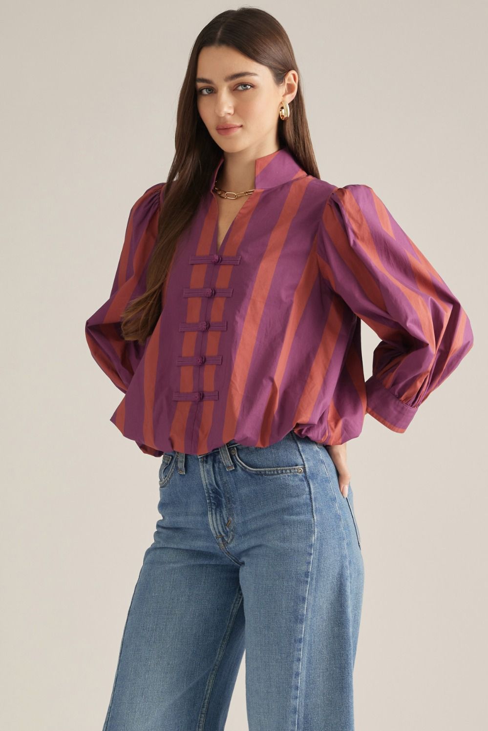 Front view of plum and rust striped blouse with stand collar, decorative frog-button front and puff sleeves.
