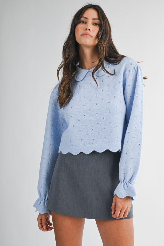 Powder blue eyelet knit sweater with long puff sleeves and scalloped trim, styled with a charcoal mini skirt — chic fall look.