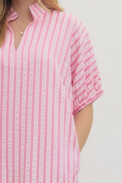 Pink and white striped shirt worn by a person on a light gray background