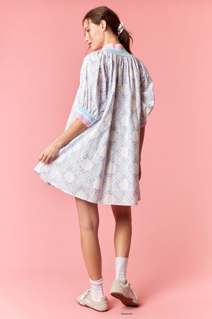 Woman wearing a light-colored dress with a subtle pattern on a pink background