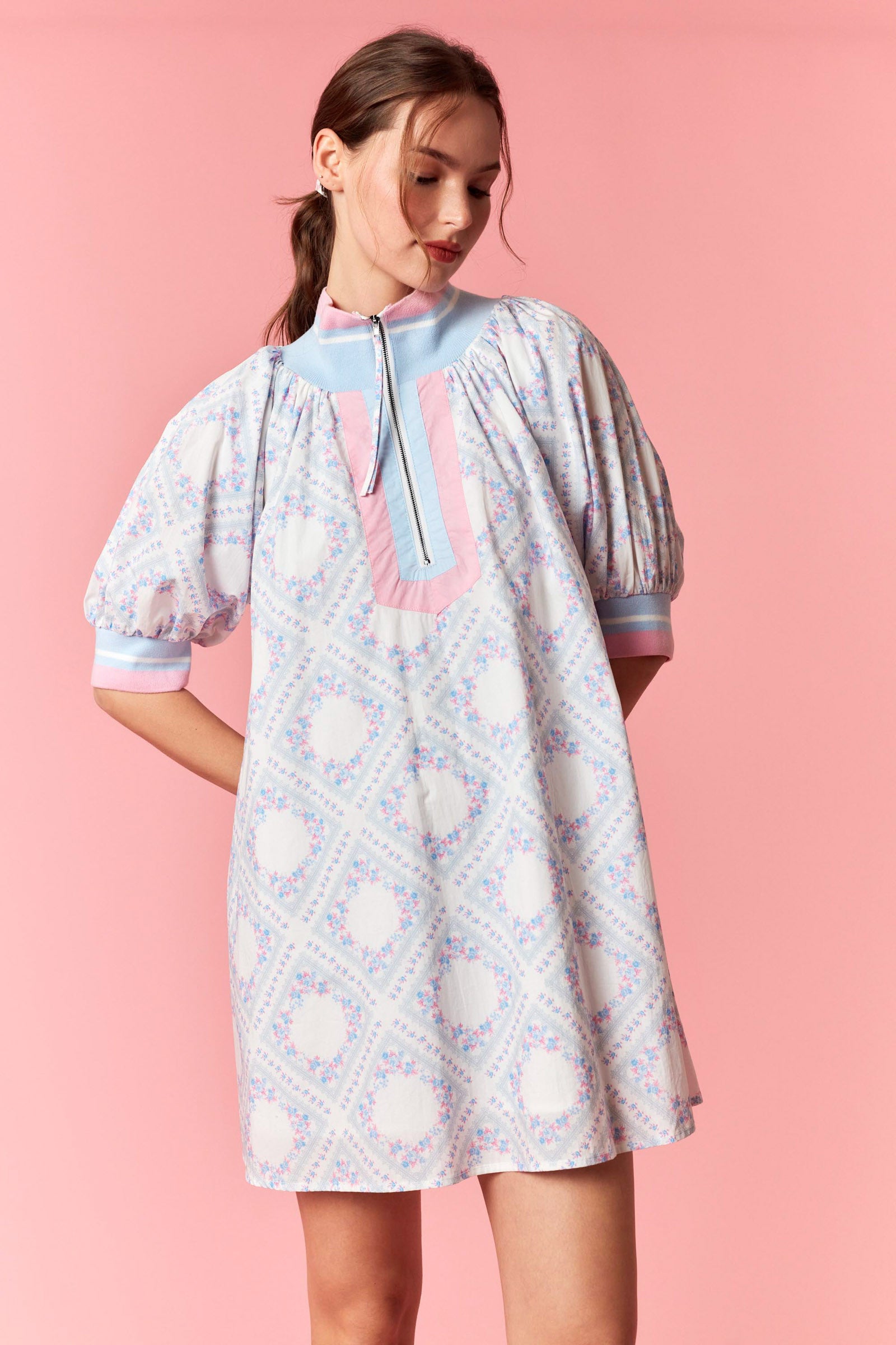 Woman wearing a patterned dress against a pink background