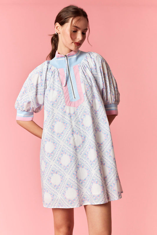 Woman wearing a patterned dress against a pink background