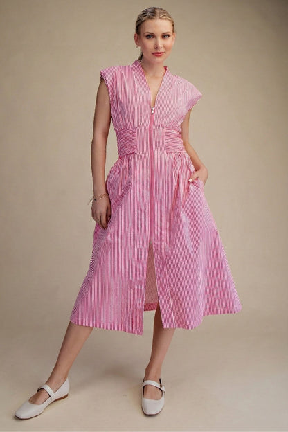 Woman wearing a pink striped dress against a beige background