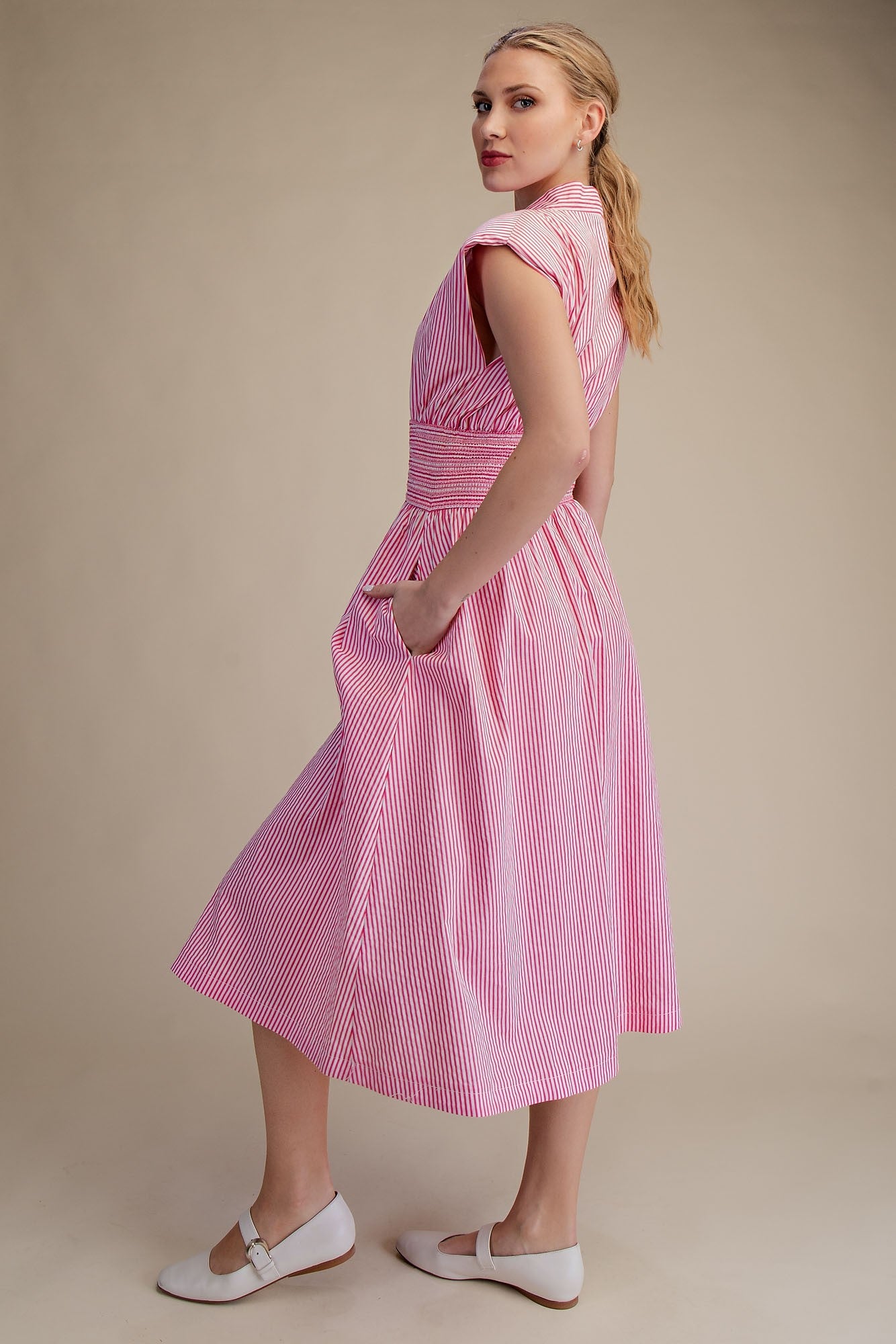 Woman wearing a pink dress with a beige background