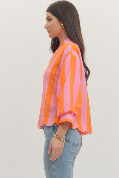 Woman wearing a colorful striped shirt and jeans on a plain background