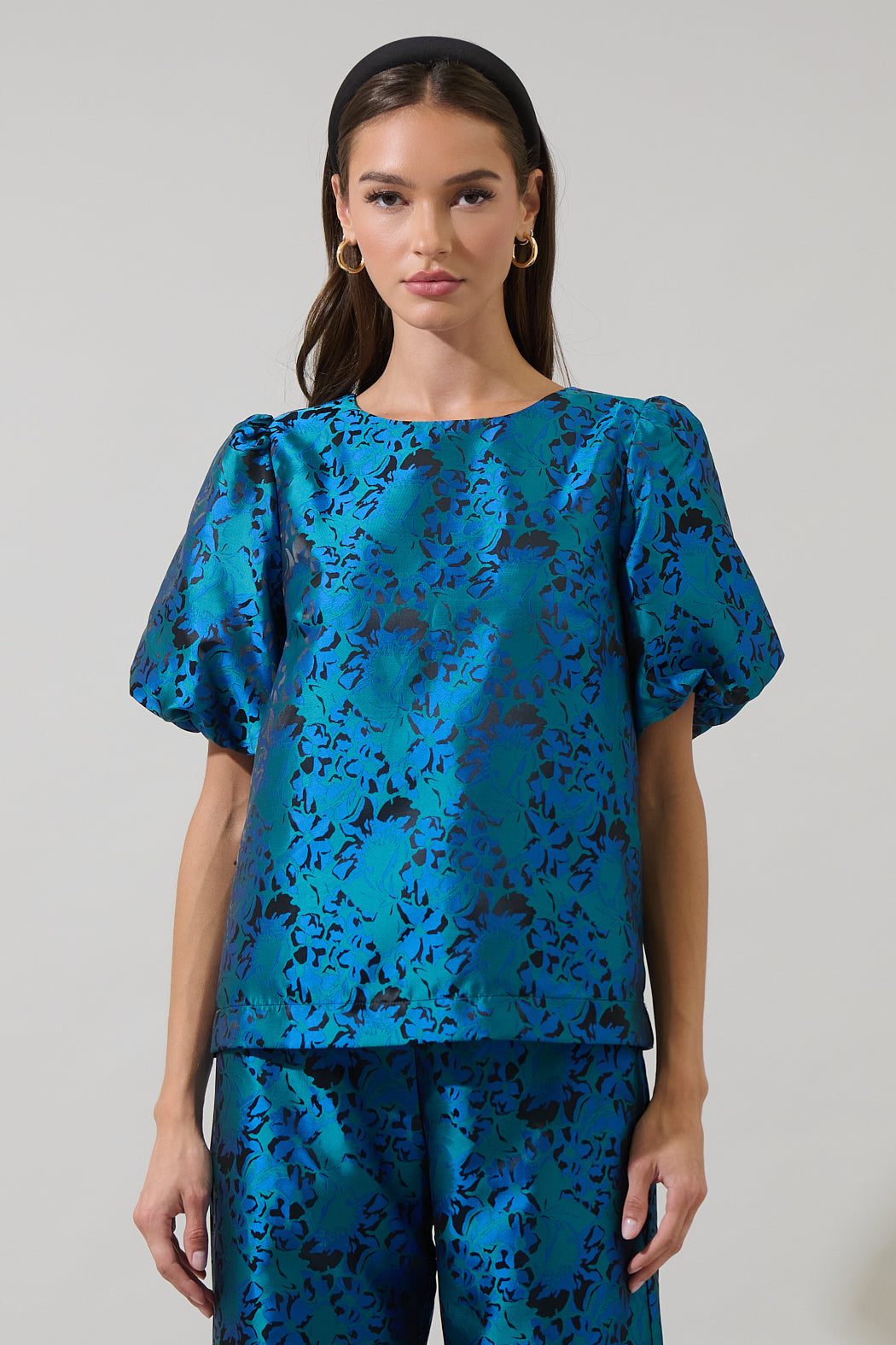 Model wearing a metallic teal jacquard puff sleeve top with a round neckline and relaxed fit — statement evening blouse from Milo & Lily Boutique.