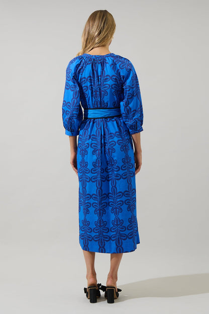 Back view of The Autumn Sky Midi, showing the gathered waist with self-tie sash and bold navy floral pattern on cobalt blue fabric.