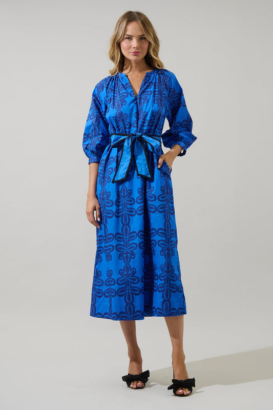 Model wearing The Autumn Sky Midi, a cobalt blue floral print belted midi dress with puff sleeves and a v-neckline — styled with black bow heels for a chic fall look.