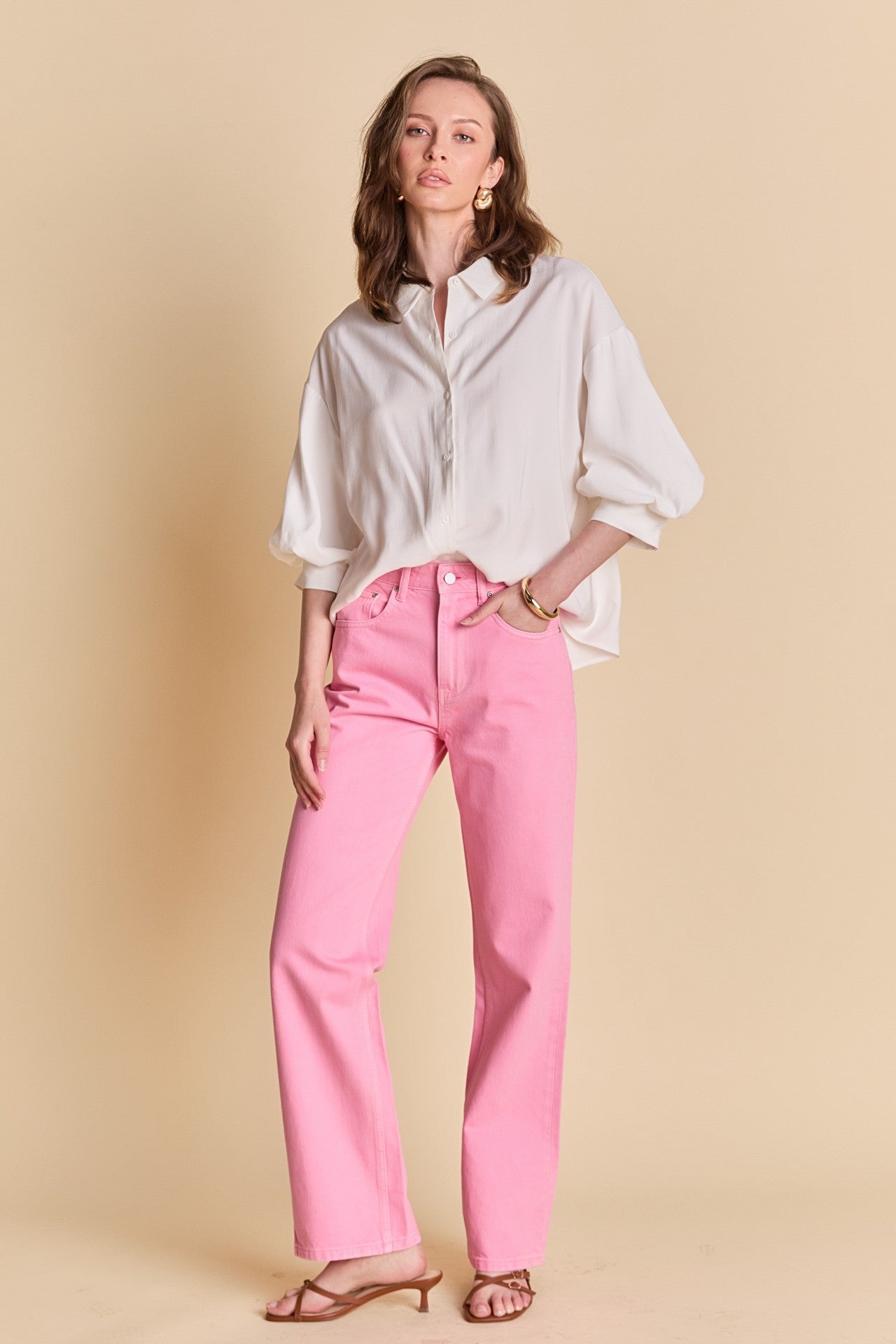 Woman wearing a white shirt and pink pants on a beige background