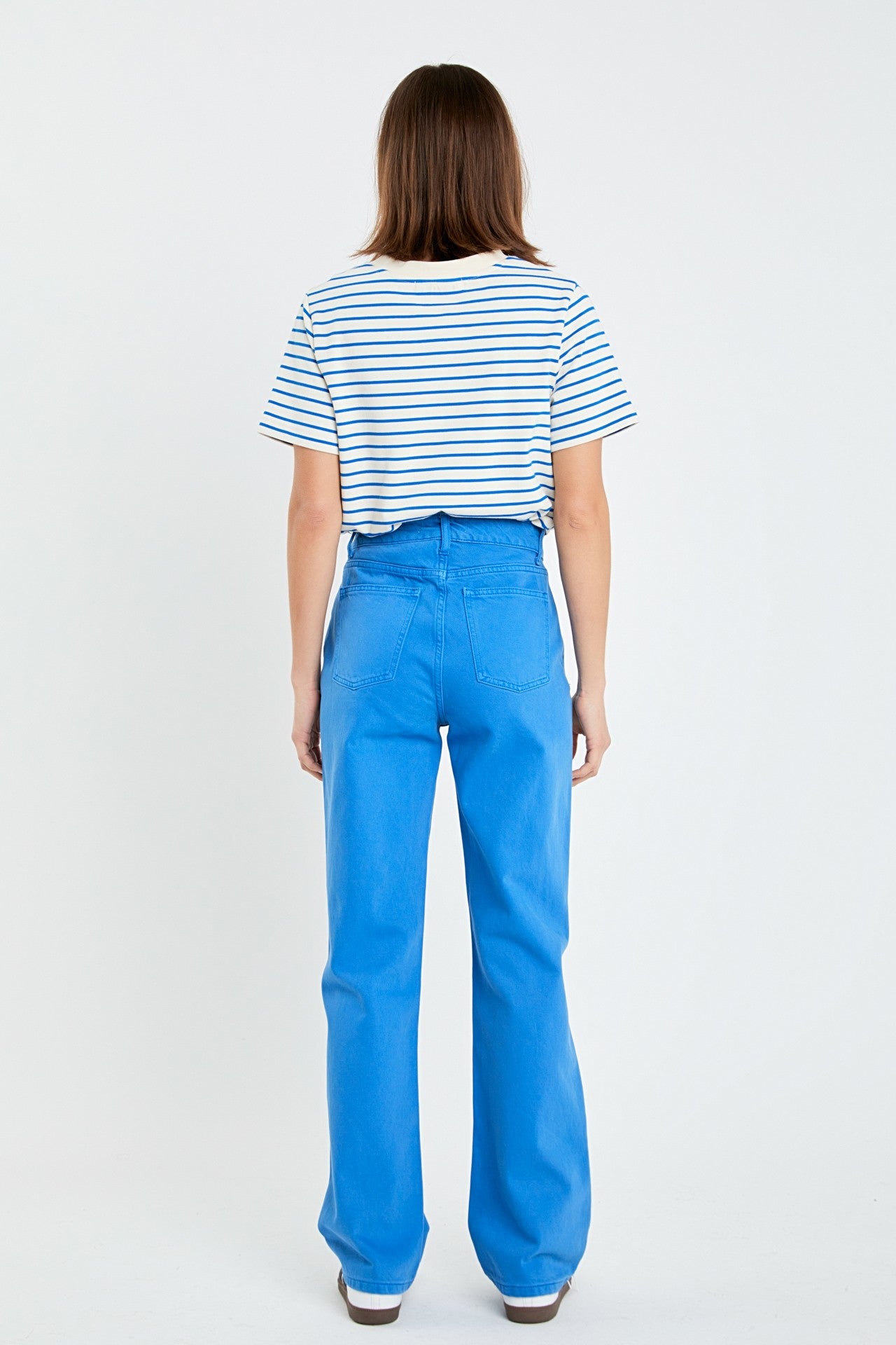 Person wearing a striped shirt and blue pants on a white background
