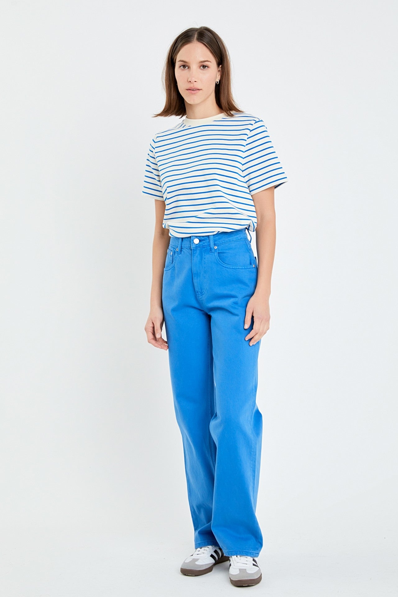 Person wearing a striped shirt and blue pants on a white background