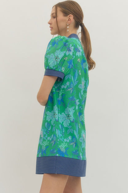 Woman wearing a green floral dress with a plain background