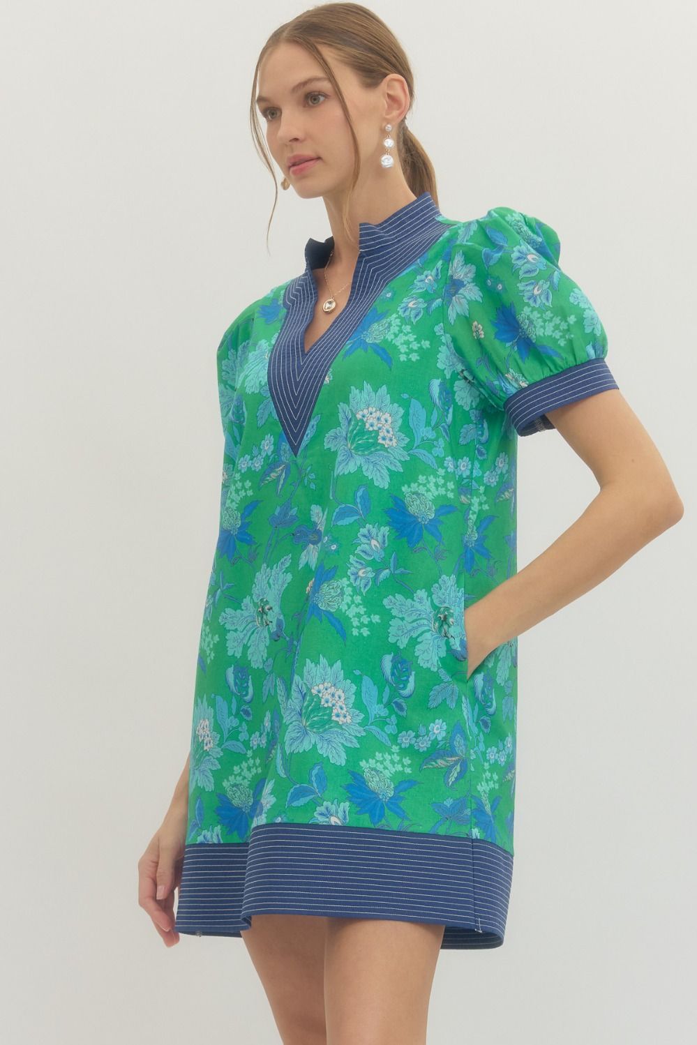 Woman wearing a green floral dress with blue accents on a white background