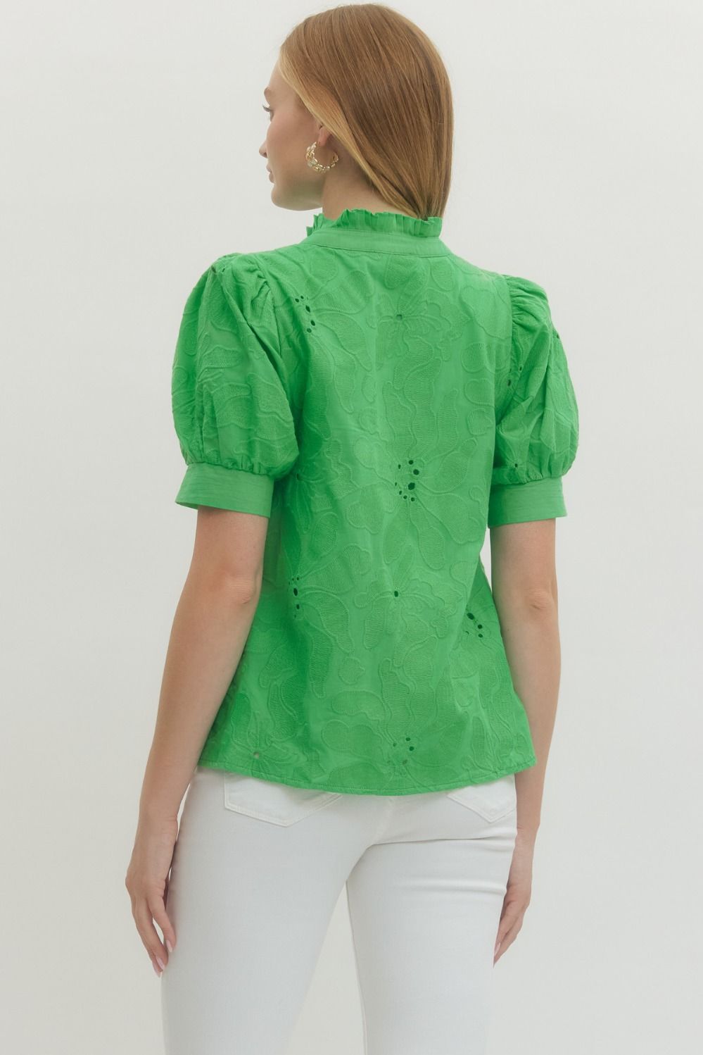 Woman wearing a green blouse with puff sleeves against a white background