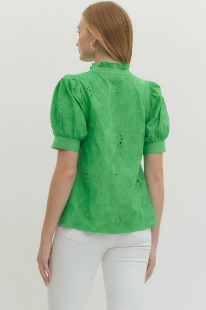 Woman wearing a green blouse with puff sleeves against a white background