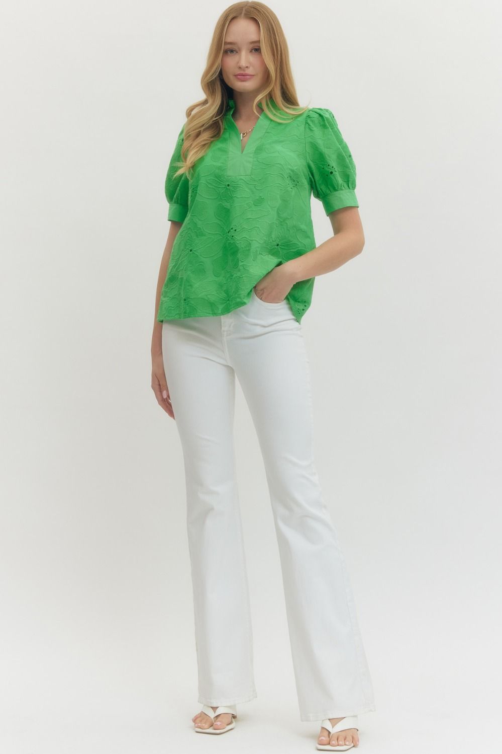 Woman wearing a green blouse and white pants on a white background