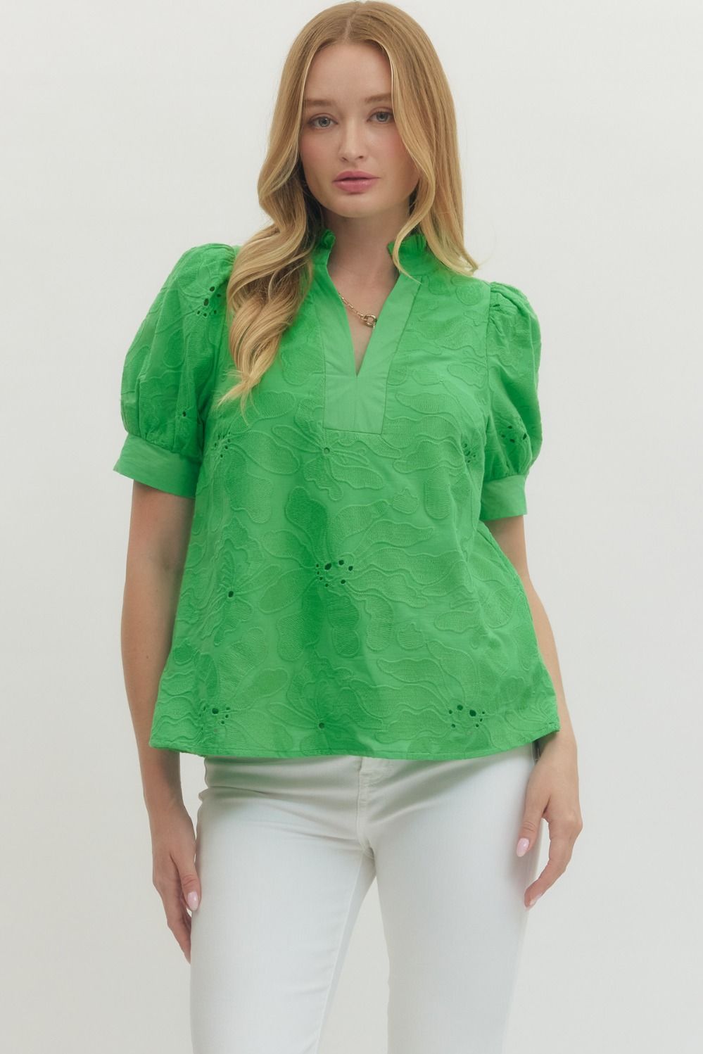 Woman wearing a green blouse with puff sleeves on a white background