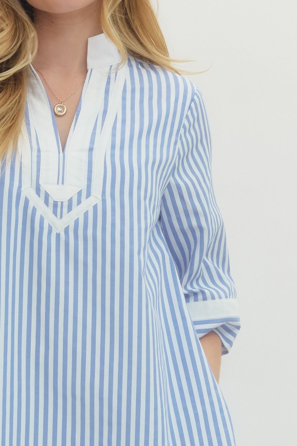 Blue and white striped shirt worn by a person on a plain background