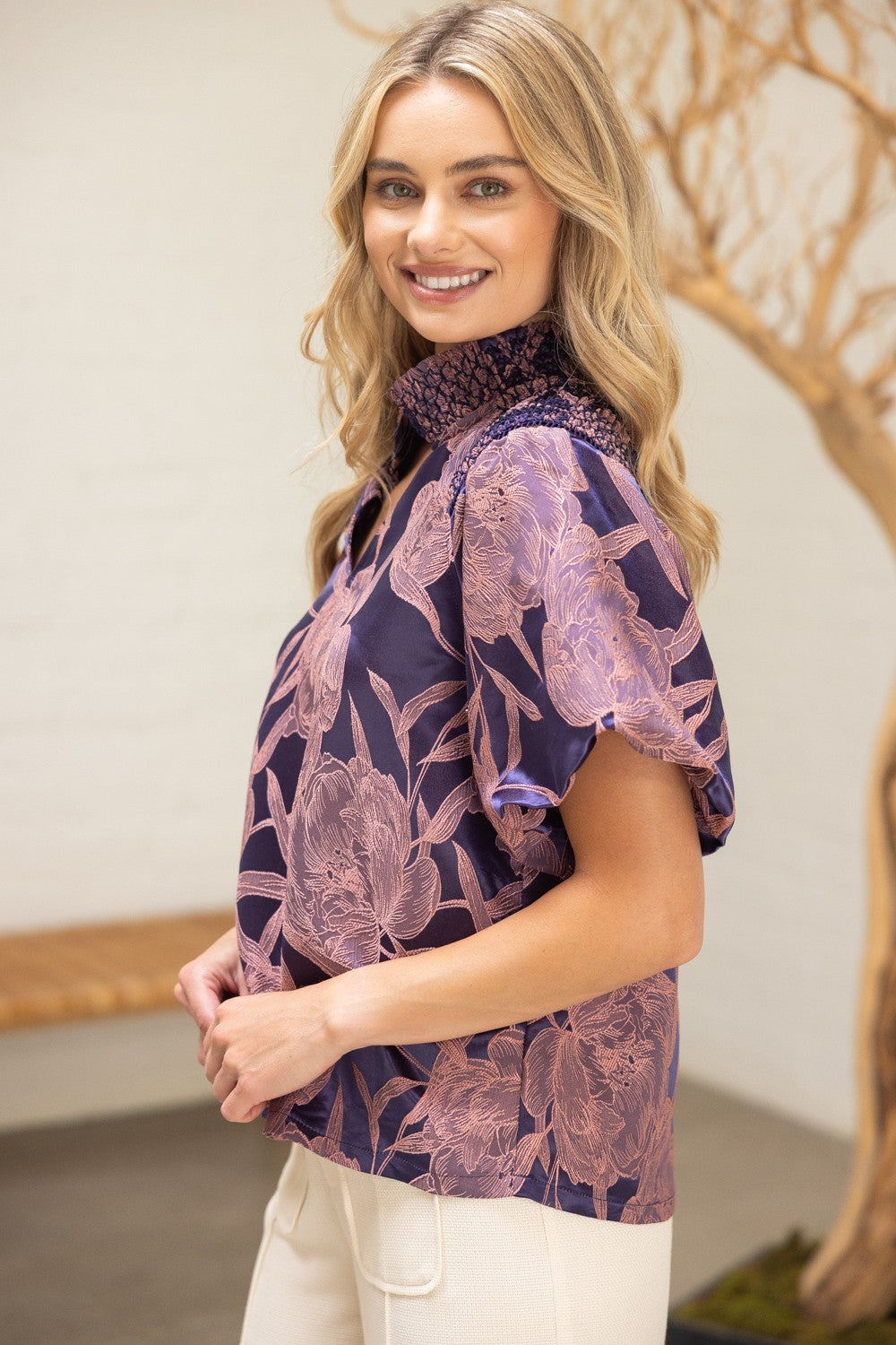 Side profile of The Twilight Bloom Top showing ruffled collar, flutter sleeve, and soft satin sheen.